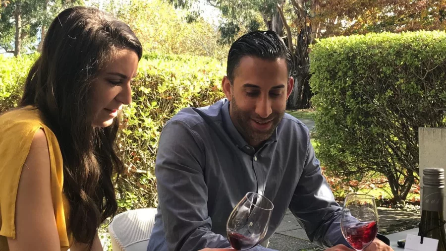 Couple enjoying a wine tasting at a Marlborough vineyard, seated outdoors.