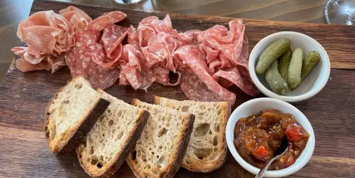 Wooden board with artisan bread, salami, cornichons, and chutney at Cloudy Bay Winery.