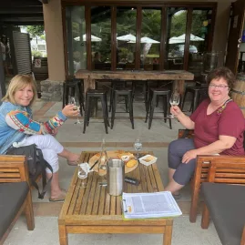 Two women toasting with wine at Forrest Wines outdoor seating area.
