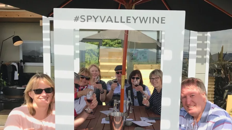 Group wine tasting at Spy Valley framed by branded photo prop