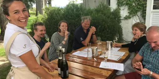 Group enjoying a guided wine tasting at an outdoor rustic table in Marlborough