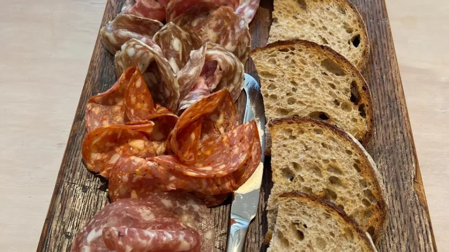 Charcuterie board with sliced meats, pickles, chutney, and sourdough bread