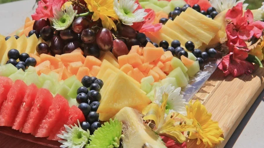 Colourful fresh fruit platter with grapes, melon, pineapple and edible flowers, served during a Marlborough wine and gourmet picnic.