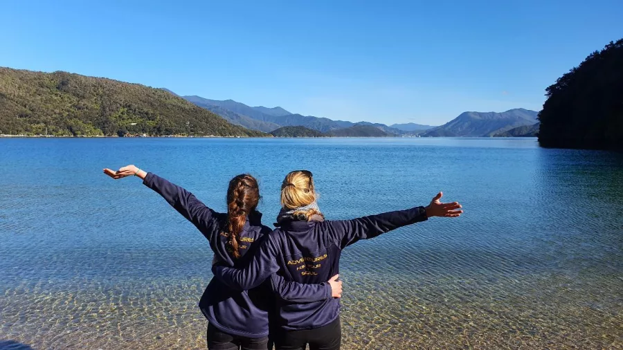 Two women enjoying the view at a clear beach in the Marlborough Sounds.