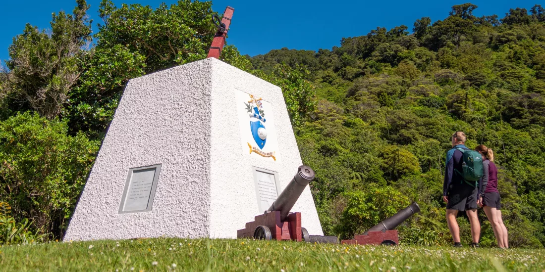 Couple viewing Captain Cook monument surrounded by native bush at Ship Cove