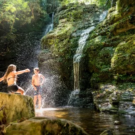 Two children enjoying a swim at Ship Cove Waterfall on the Queen Charlotte Track