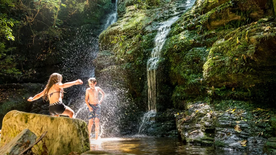 Two children enjoying a swim at Ship Cove Waterfall on the Queen Charlotte Track