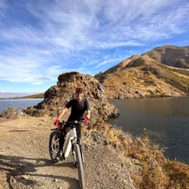 Guide Harry cycling solo along the Benmore Peninsula trail beside Lake Benmore in New Zealand.