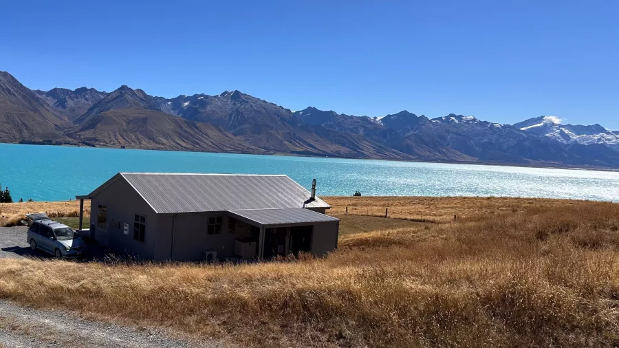Scenic lodge at Braemar Station overlooking the turquoise waters of Lake Pukaki with snow-capped mountains in the background.