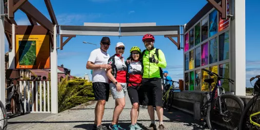 Group of cyclists posing at the Greymouth start point of the West Coast Wilderness Trail in New Zealand.