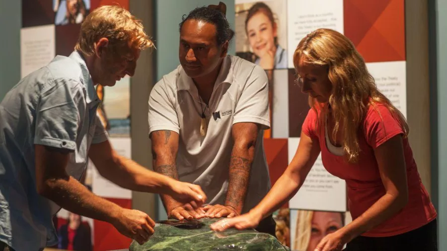 Visitors gathered around and touching a pounamu (greenstone) display at the Waitangi Treaty Grounds Museum