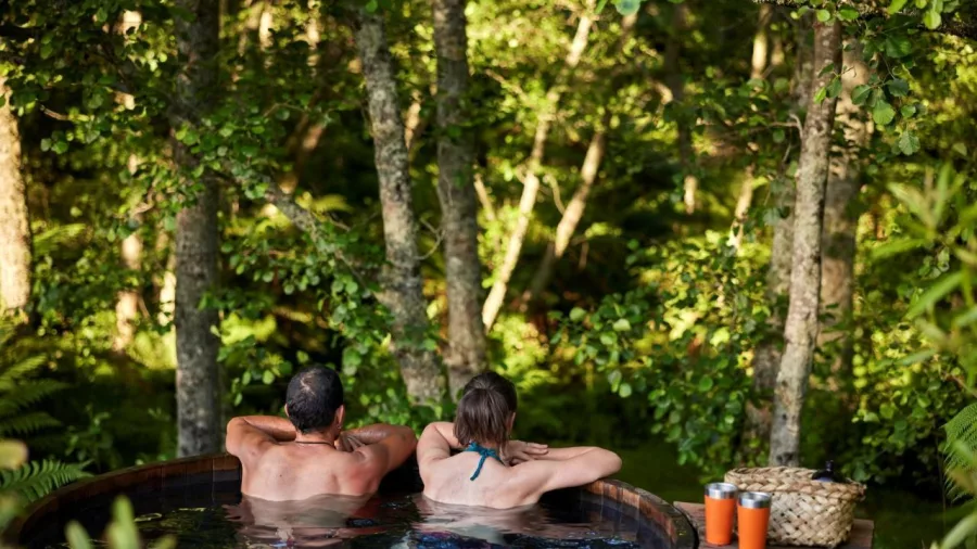 Couple soaking in a forest-view hot tub with native bush setting at Secret Spot Rotorua