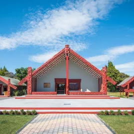 Traditional Māori marae (meeting house) at Te Puia, set against a clear blue sky in Rotorua