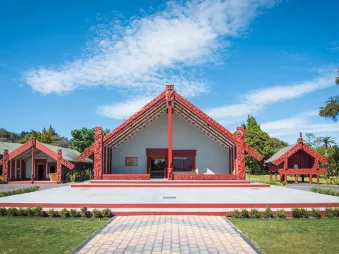 Traditional Māori marae (meeting house) at Te Puia, set against a clear blue sky in Rotorua