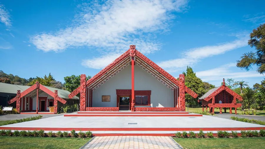 Traditional Māori marae (meeting house) at Te Puia, set against a clear blue sky in Rotorua