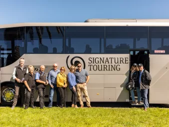 Tour group standing beside a Signature coach from Grand Pacific Tours