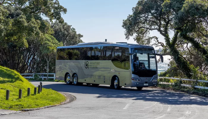 Signature coach from Grand Pacific Tours driving along a scenic coastal road
