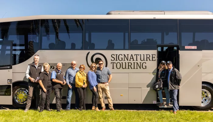 Tour group standing beside a Signature coach from Grand Pacific Tours