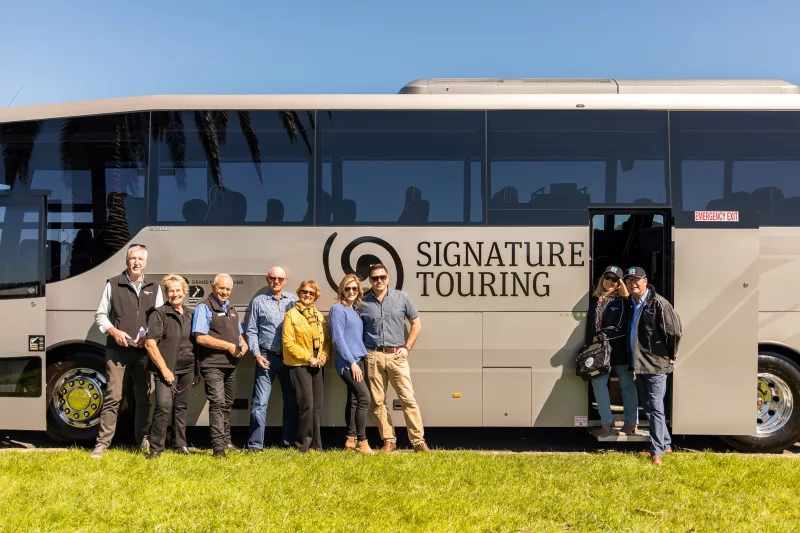 Tour group standing beside a Signature coach from Grand Pacific Tours