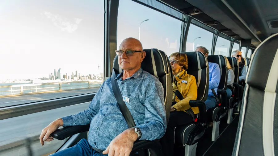Passenger enjoying a window seat view on the Signature coach by Grand Pacific Tours