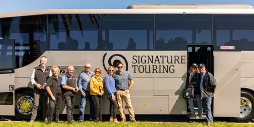 Tour group standing beside a Signature coach from Grand Pacific Tours