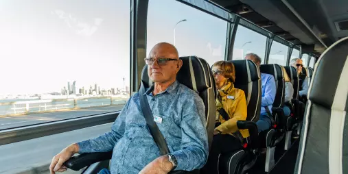 Passenger enjoying a window seat view on the Signature coach by Grand Pacific Tours