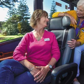 Two guests chatting inside the Ultimate coach with scenic views outside