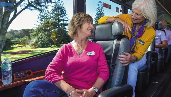Two guests chatting inside the Ultimate coach with scenic views outside