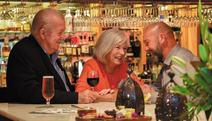 Guests enjoying wine and conversation at the bar during a Grand Pacific Ultimate Tour