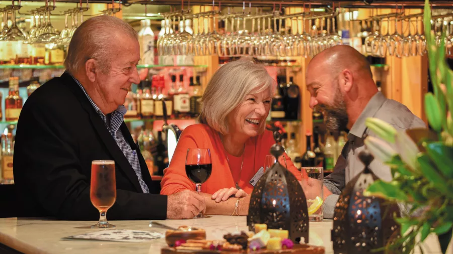 Guests enjoying wine and conversation at the bar during a Grand Pacific Ultimate Tour
