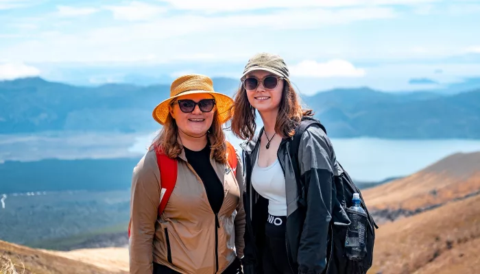 Hikers enjoying the Tongariro Alpine Crossing with mountain views and Lake Taupō in the distance, New Zealand.
