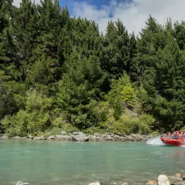 Travellers speeding through turquoise waters on the famous Shotover Jet in Queenstown, New Zealand.