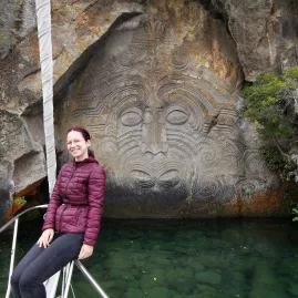 Woman posing in front of the Māori rock carvings at Lake Taupō, New Zealand