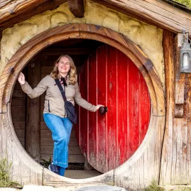 Smiling traveller at iconic red door in Hobbiton Movie Set, Matamata