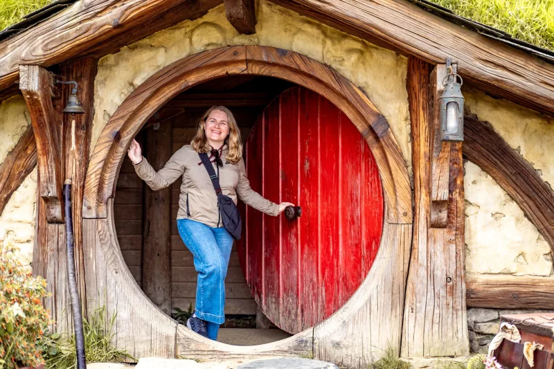 Smiling traveller at iconic red door in Hobbiton Movie Set, Matamata