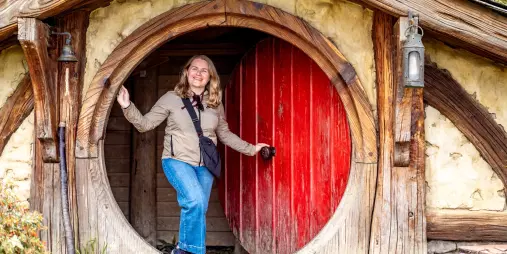 Smiling traveller at iconic red door in Hobbiton Movie Set, Matamata