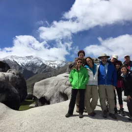 Tramping group posing among giant limestone boulders at Castle Hill in Canterbury