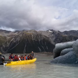 Tourists on a boat exploring icebergs at Tasman Lake in Aoraki Mount Cook National Park