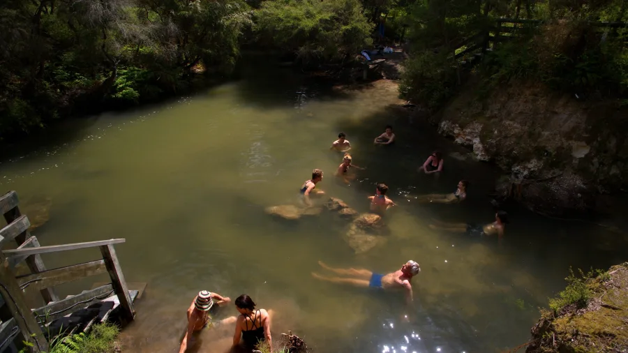 Travellers swimming and relaxing in the natural hot spring at Kerosene Creek near Rotorua
