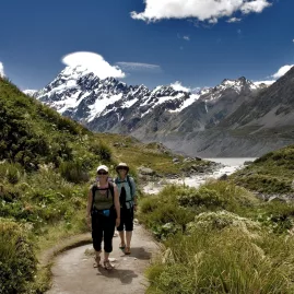 Two walkers on the Hooker Valley Track with Aoraki Mount Cook in the background