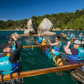 Waka tour group passing Split Apple Rock in Abel Tasman National Park, New Zealand