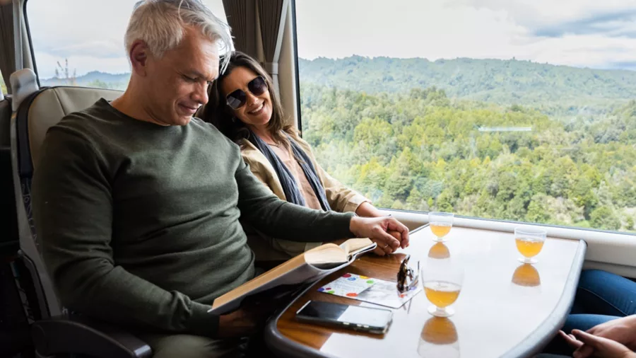 Couple relaxing with drinks on Northern Explorer Train, Auckland, Scenic, North Island