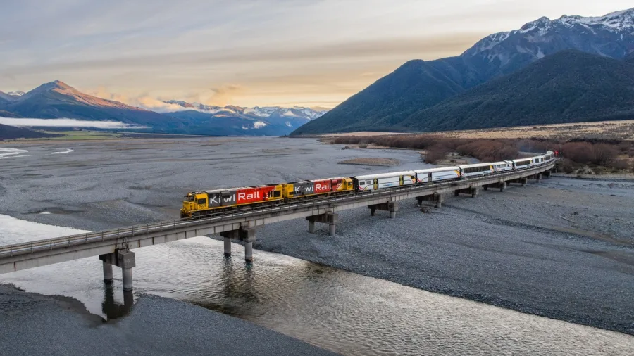 TranzAlpine train crossing Cass River with Southern Alps backdrop