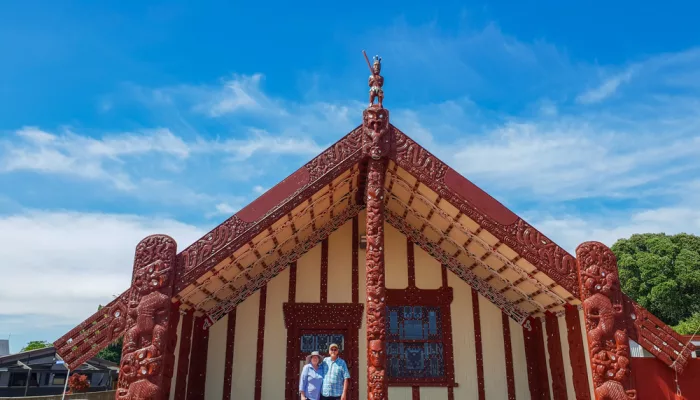 Visitors outside carved Māori meeting house at Ohinemutu in Rotorua