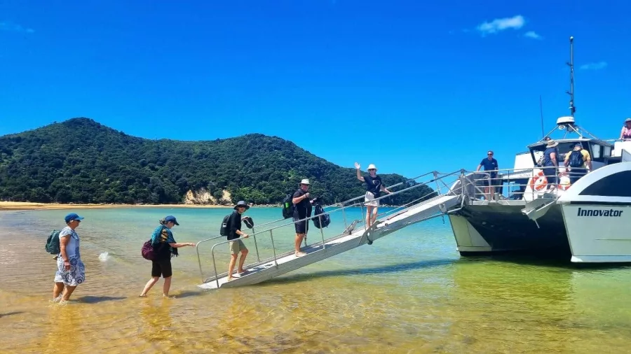 Guests boarding Abel Tasman tour boat at Kaiteriteri Beach