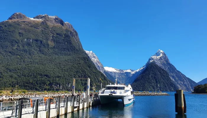 Cruise boat docked at Milford Sound with Mitre Peak in view
