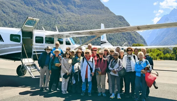 Group photo beside scenic flight plane at Milford Sound airstrip