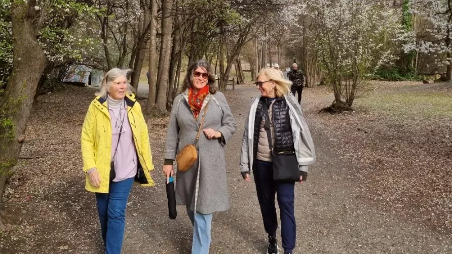 Guests walking under spring blossoms in Arrowtown on a MoaTrek tour