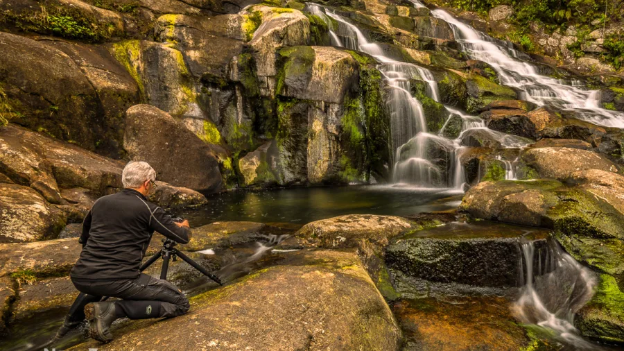 Photographer shooting a tiered waterfall along Coromandel’s coast