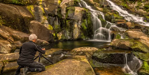 Photographer shooting a tiered waterfall along Coromandel’s coast